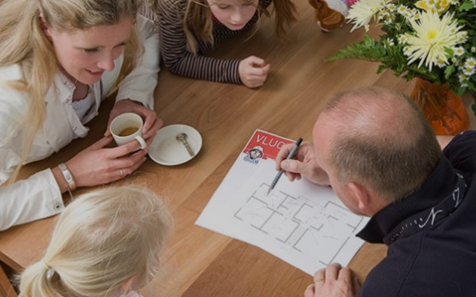 meneer schetst vluchtplan op papier aan drie vrouwen