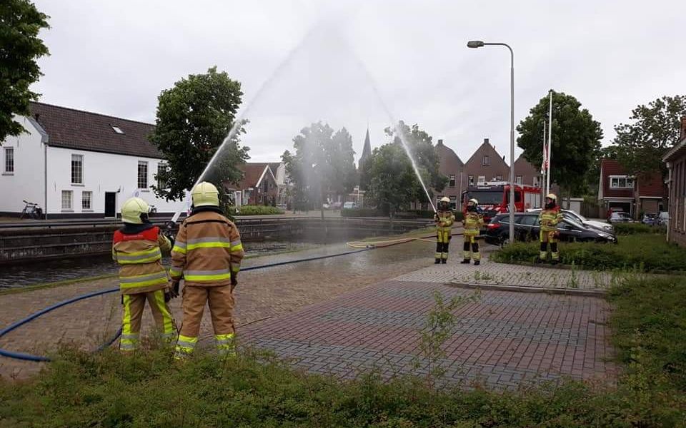 ereboog met blusslang door brandweermannen